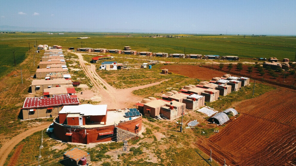 Village en triangle d'une trentaine de petites maisons, regroupées dans la plaine. Une grande maison commune ronde avec étage est à l'avant plan.